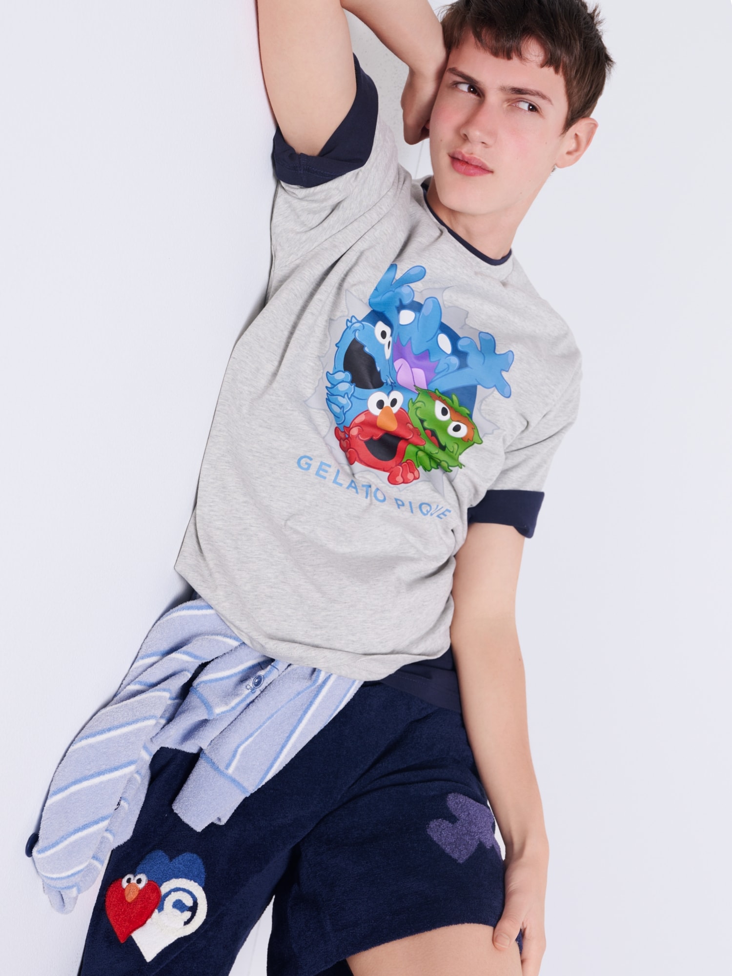 セサミキャラクター集合柄のグレーTシャツを着たモデル