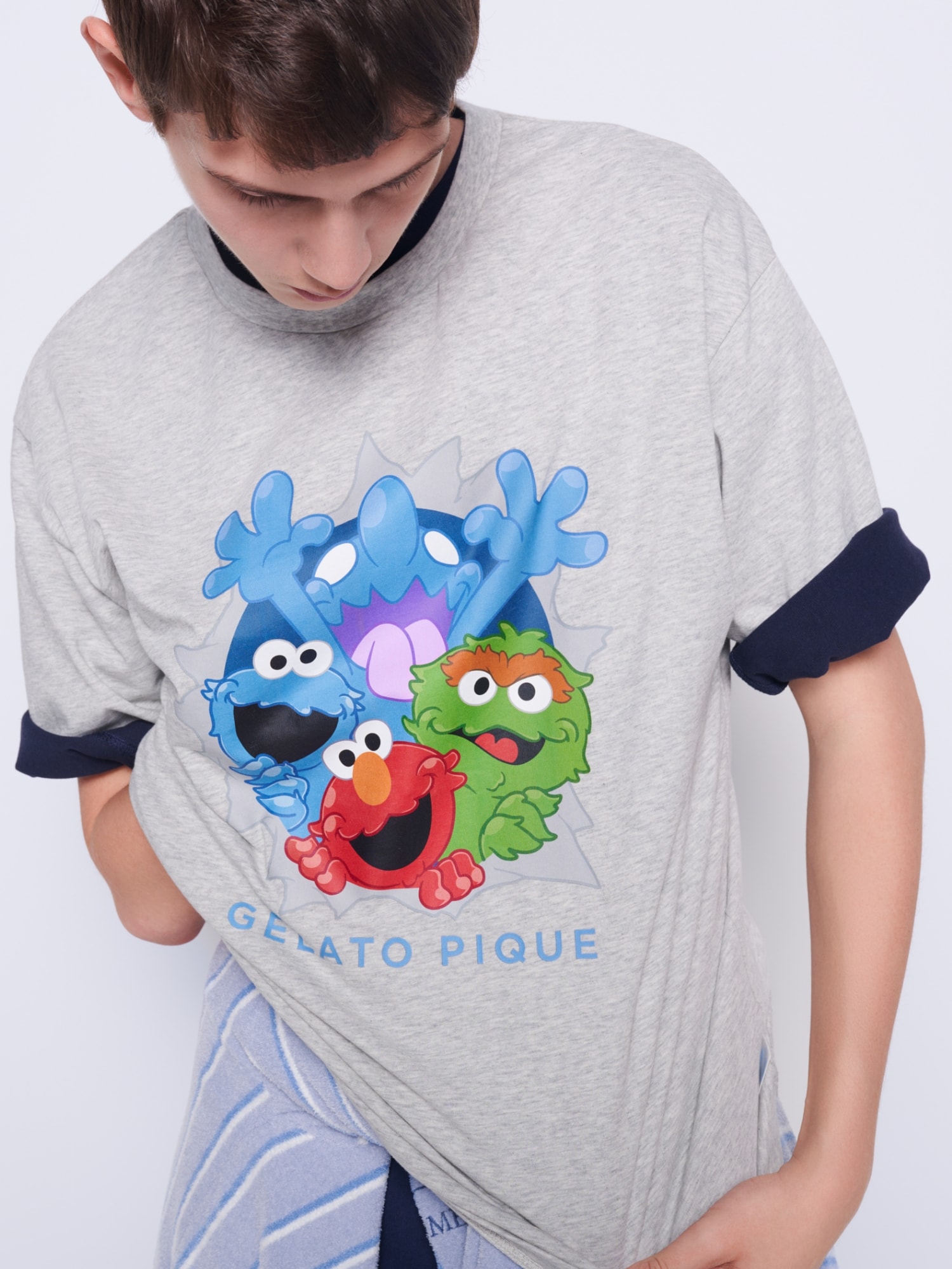 セサミキャラクター集合柄のグレーTシャツを着たモデル