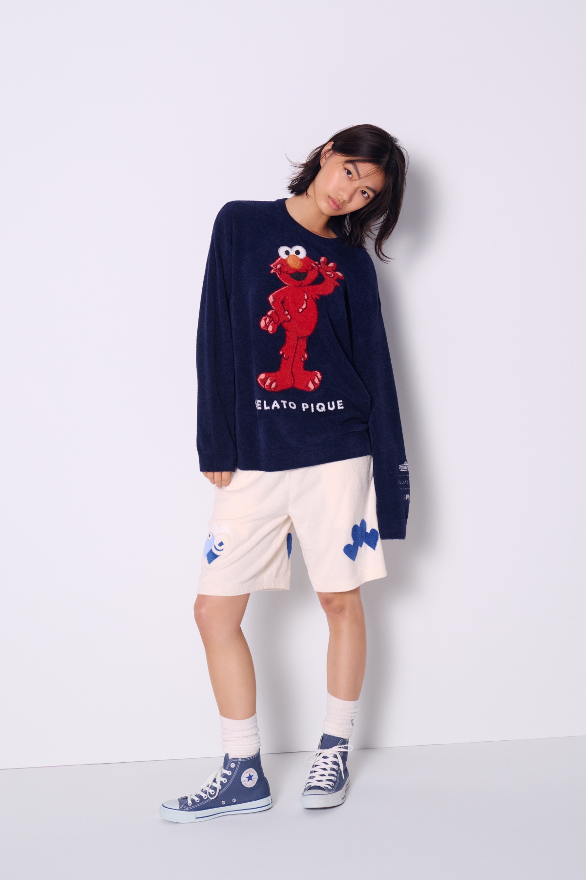 紺色のエルモ柄ニットとショートパンツを着た女性モデル